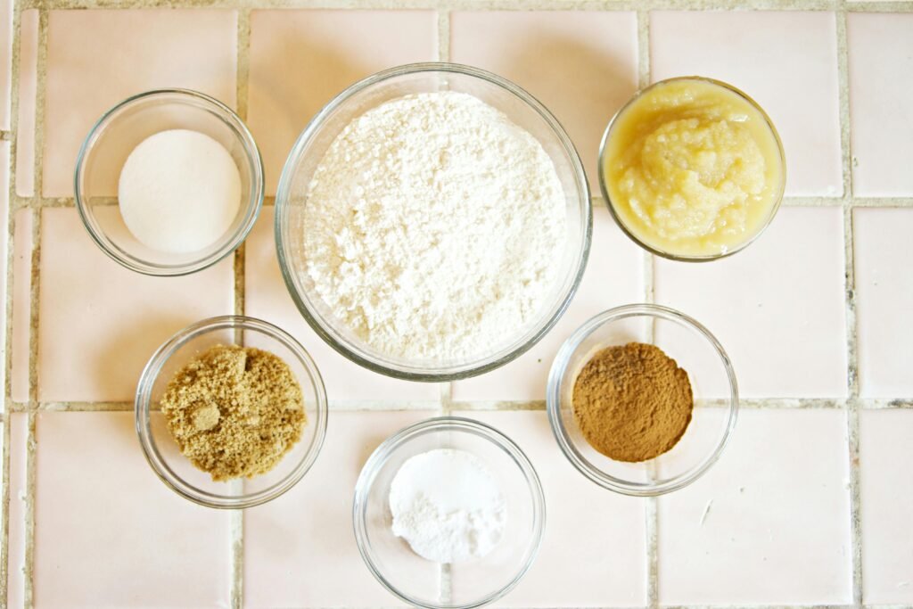 Top view of baking ingredients in bowls on a tiled surface, perfect for culinary projects.